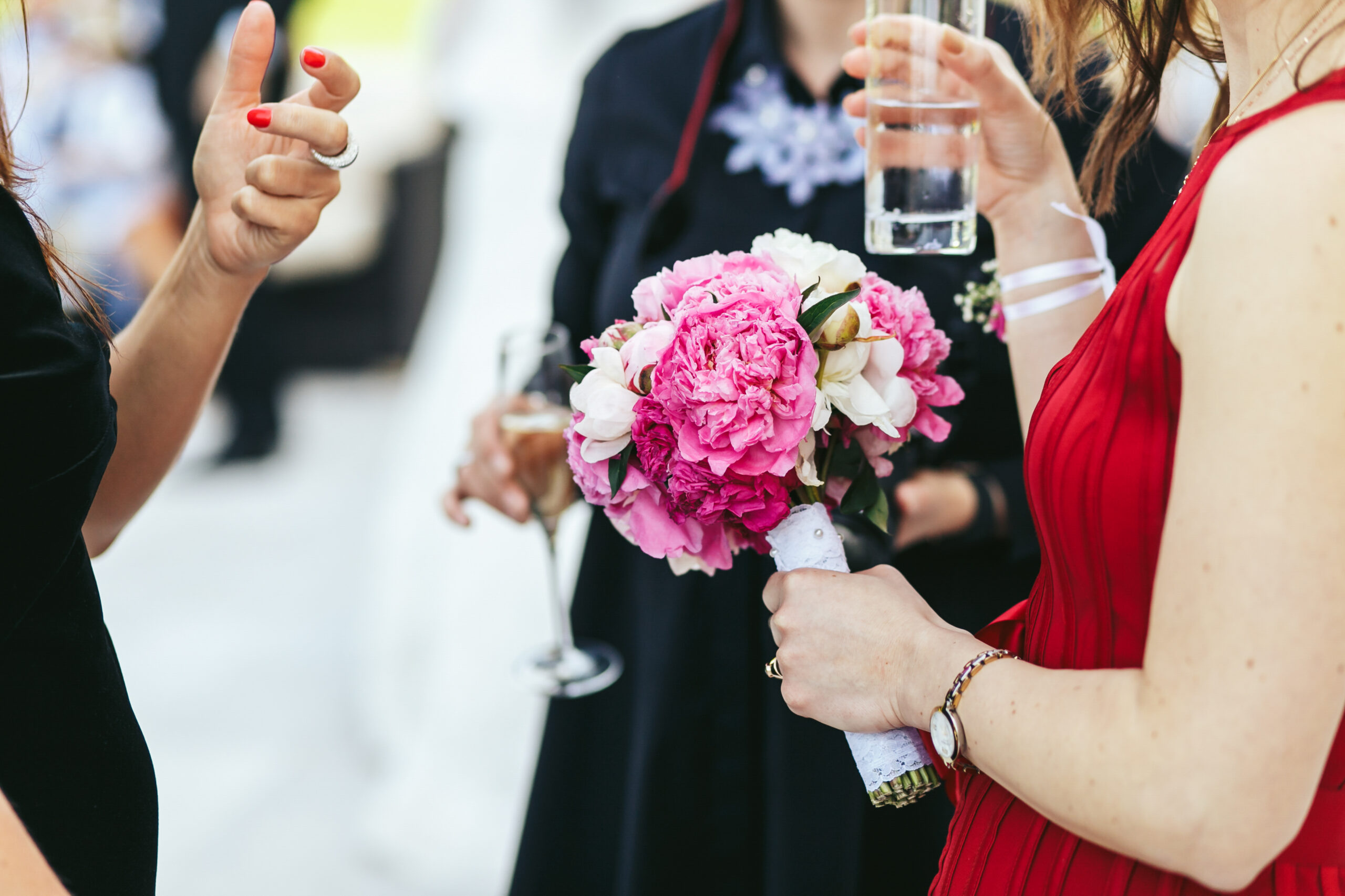 Woman in red dress holds a glass while talking with people